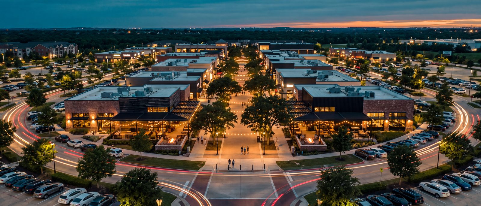 Aerial view at dusk of a suburban dining and entertainment destination developed by Brookline Development Group